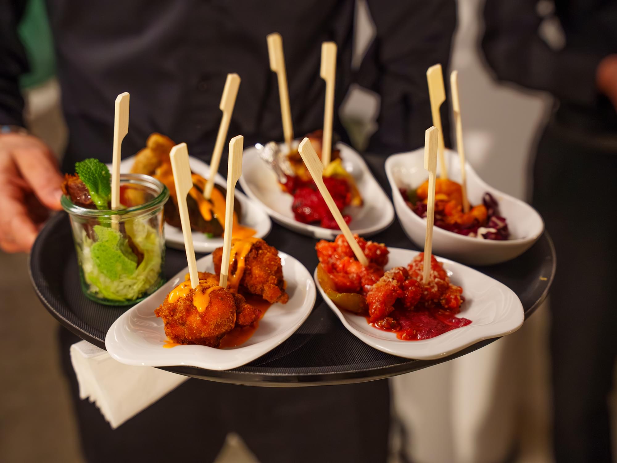 Servicekraft reicht indisches Fingerfood auf dem Tablett beim Catering