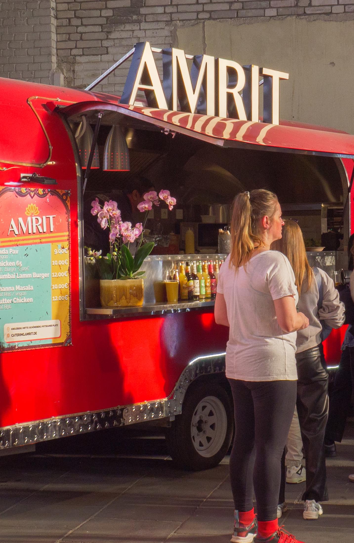 Roter AMRIT Foodtruck mit wartenden Gästen auf einem Event