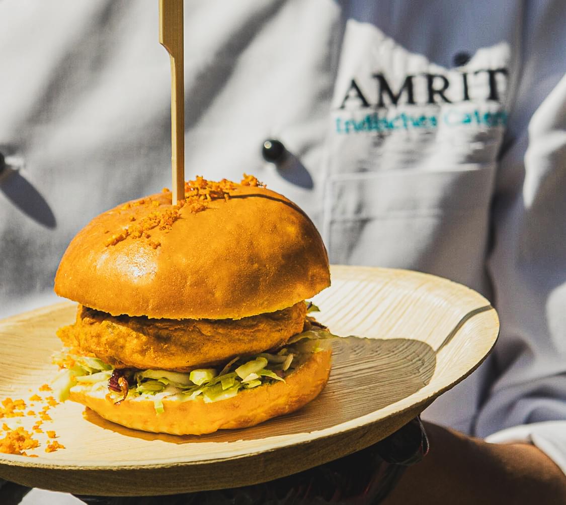 Indischer Chicken-Burger vom AMRIT Foodtruck auf dem Holzteller