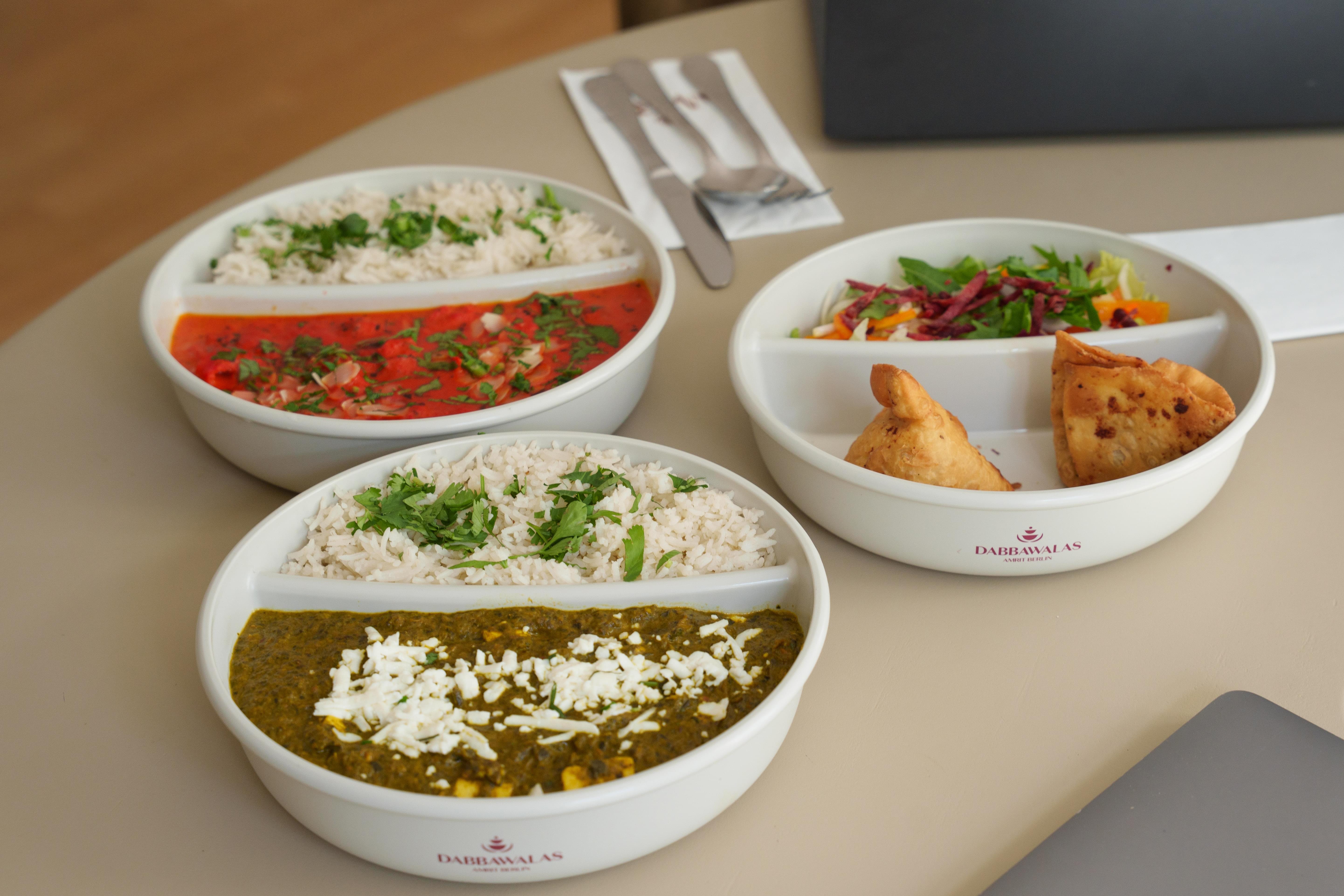 Warme Speisen, Salat und Samosas in Mehrwegschalen für das Crew Catering
