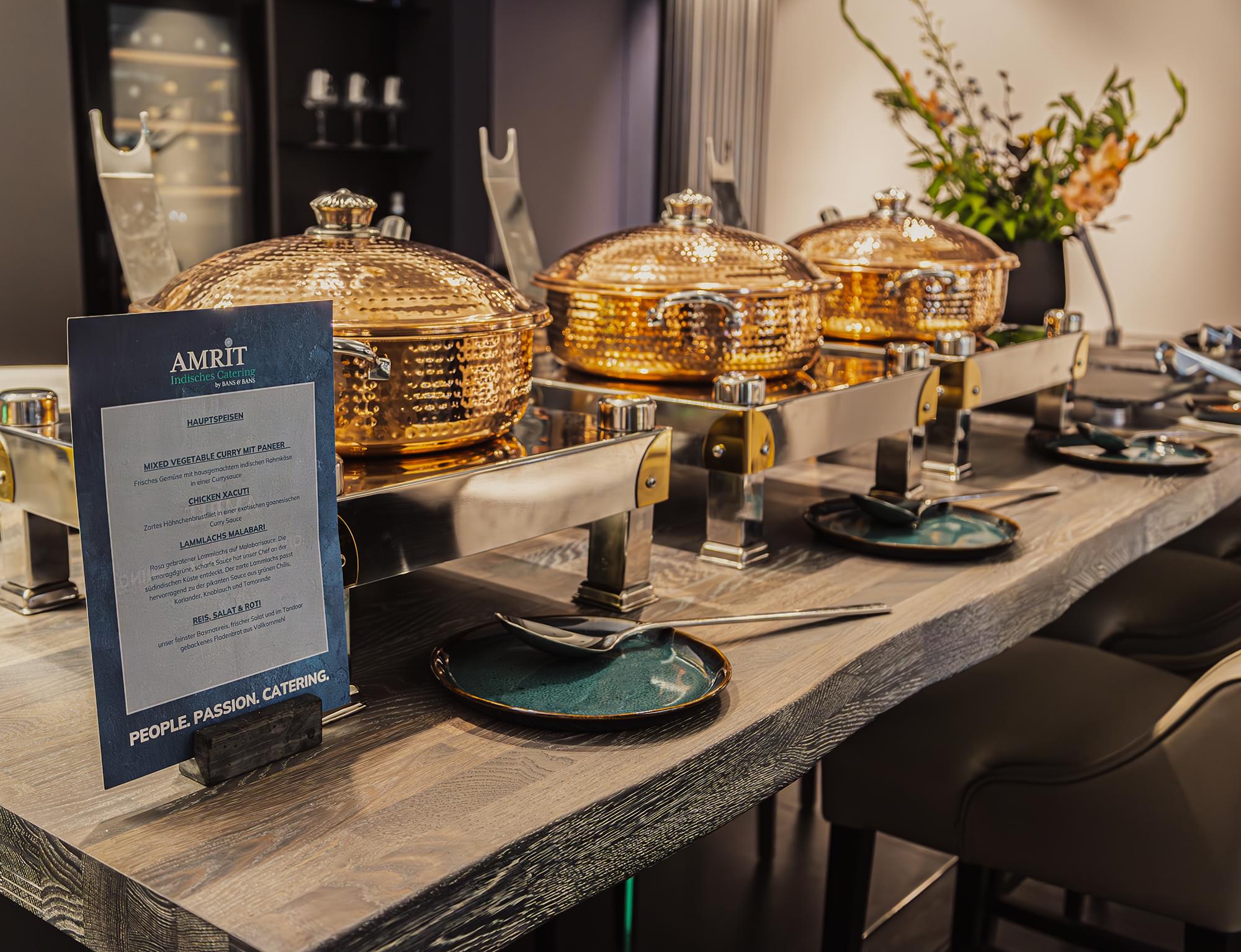 Buffet mit goldenen Chafing Dishes und Menükarte beim Eventcatering von AMRIT